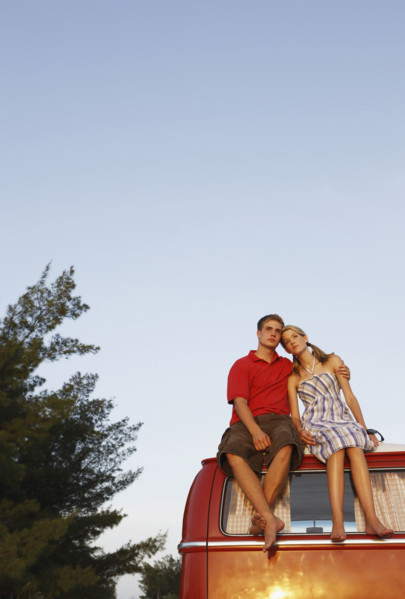 Couple watching ocean sunset from top of van. Date : 2008
