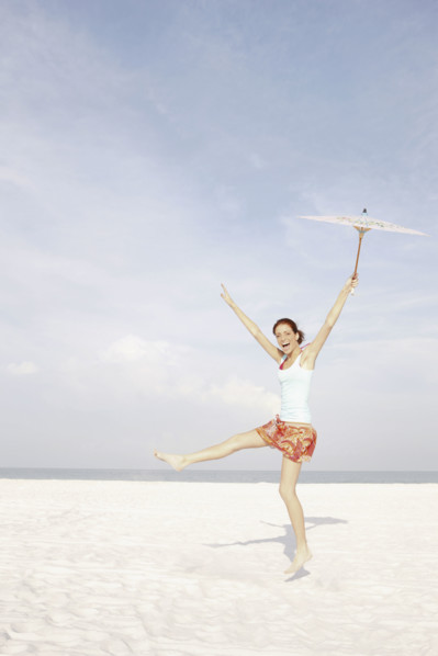 Girl holding umbrella and dancing on beach. Date : 2008
