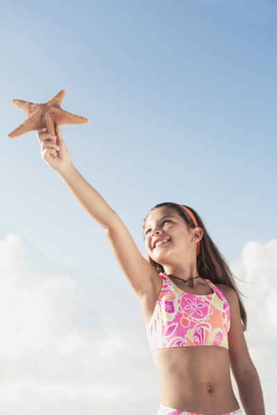 Girl in bathing suit holding up starfish. Date : 2008