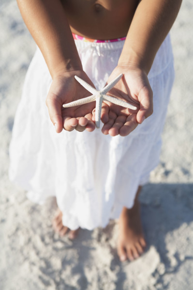 Girl on beach holding delicate starfish. Date : 2008