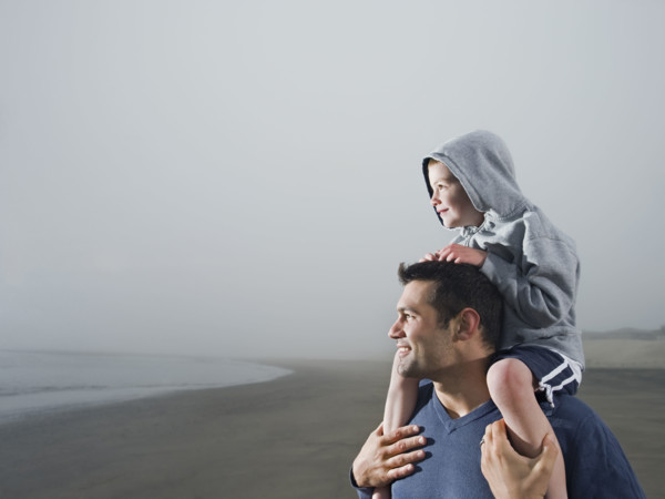 Father carrying son on shoulders on beach. Date : 2008