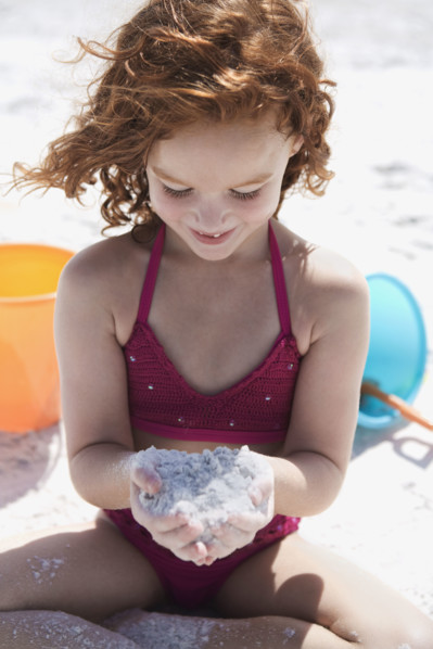 Girl in bikini cupping sand on beach. Date : 2008
