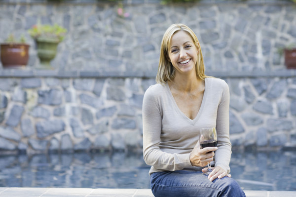 Woman with wine glass sitting on edge of swimming pool. Date : 2008