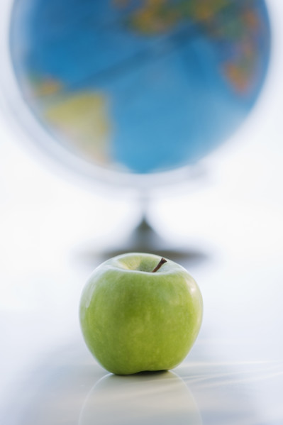 Green apple with globe in background.