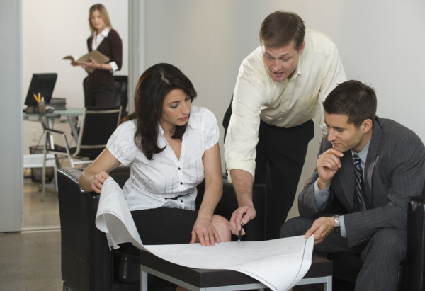 Business people examining blueprints.