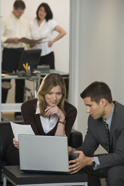 Businessman and businesswoman using laptop.