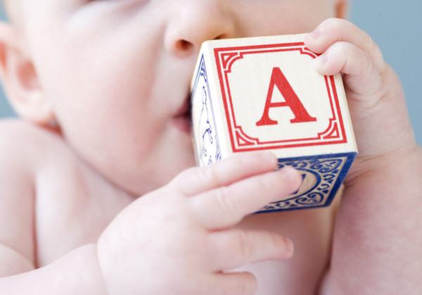 Close up of baby biting on alphabet block. Date : 2008