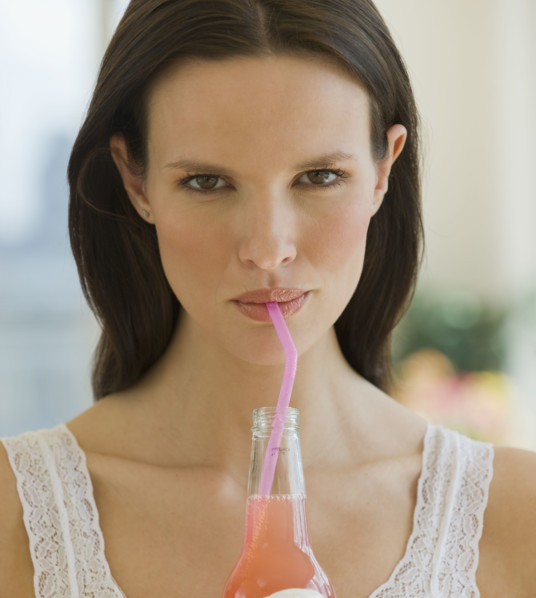 Close up of woman drinking soda from a straw.