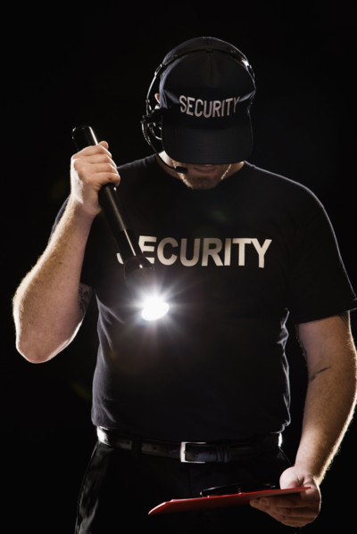 Bouncer looking at guest list with flashlight. Date: 2008