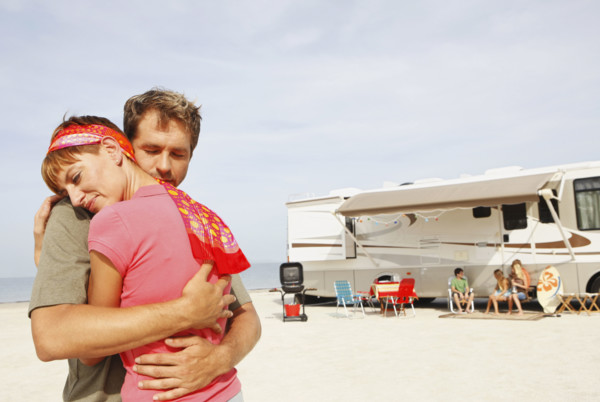 Couple hugging on beach with motor home in background. Date : 2008