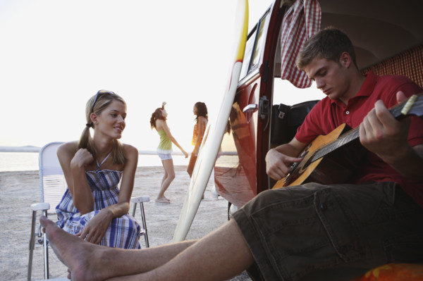 Man playing guitar in van on beach. Date : 2008