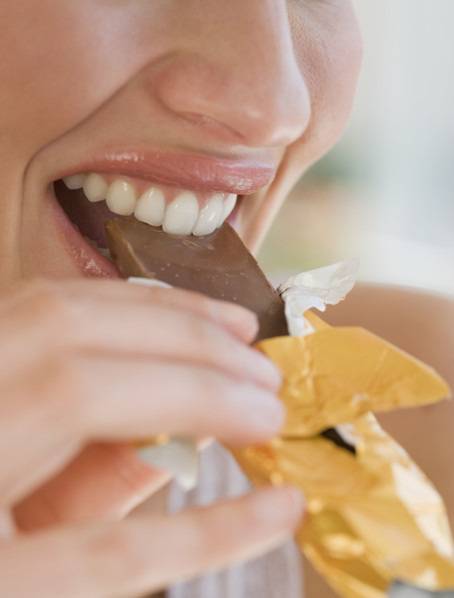 Close up of woman biting chocolate bar.