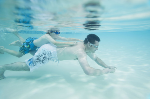 Boy swimming on father’s back underwater. Date : 2008