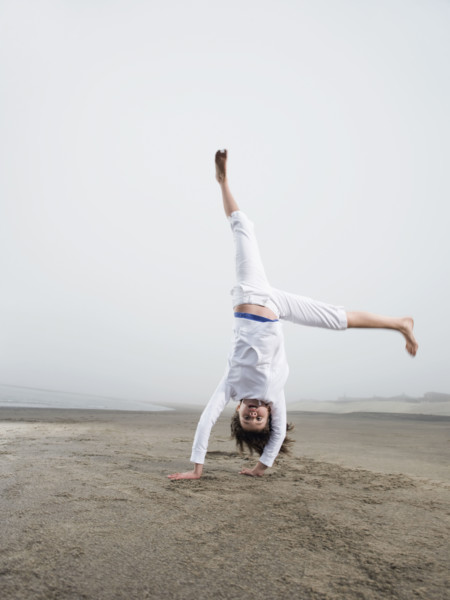 Portrait of girl doing handstand on beach. Date: 2008