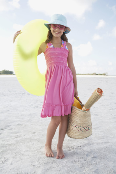 Portrait of girl holding inflatable tube and bag on beach. Date : 2008