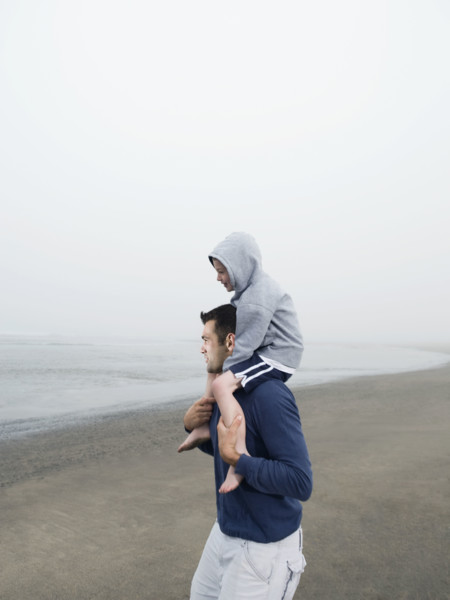 Father carrying son on shoulders on beach. Date: 2008