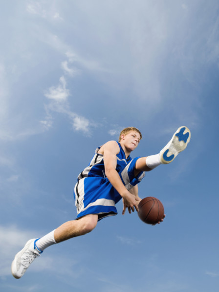 Teenage basketball player in mid-air with basketball. Date: 2008