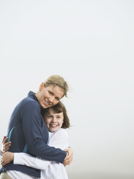 Mother and daughter hugging on beach. Date: 2008