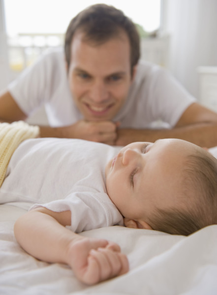 Father watching baby son sleep.