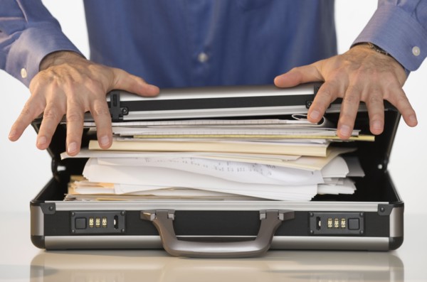 Businessman trying to close briefcase.