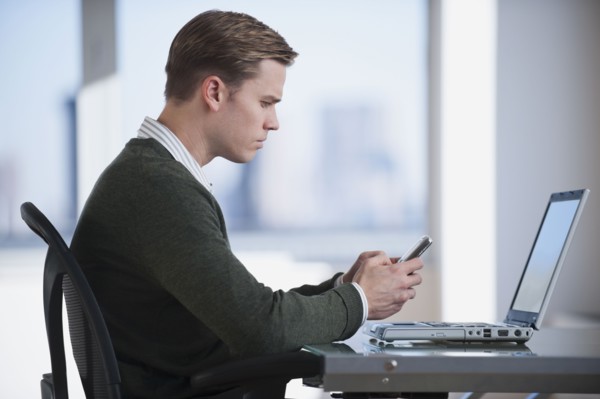 Businessman text messaging in office.