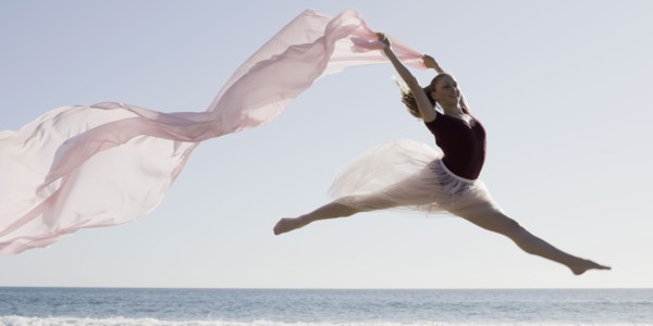 Dancer leaping on beach. Photographe : PT Images