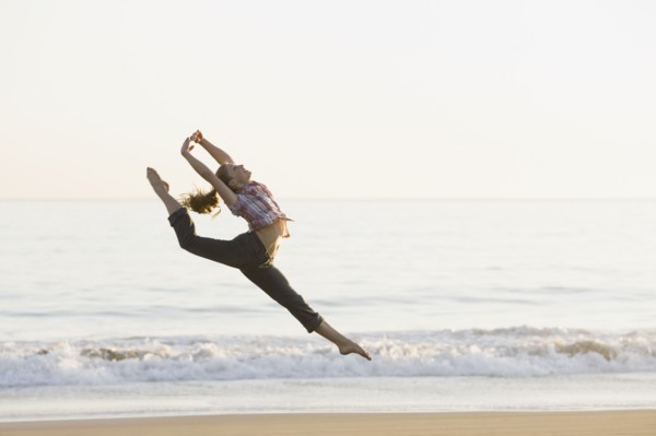 Woman dancing on beach. Photographe : PT Images