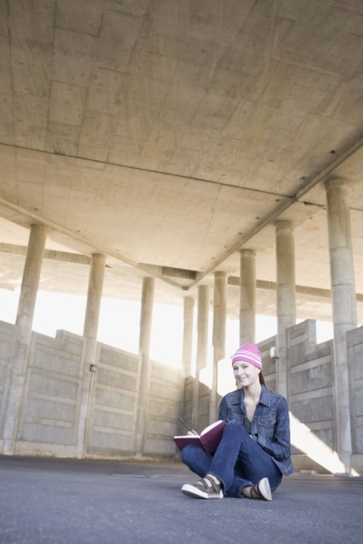 Young woman reading in urban setting. Photographe : PT Images