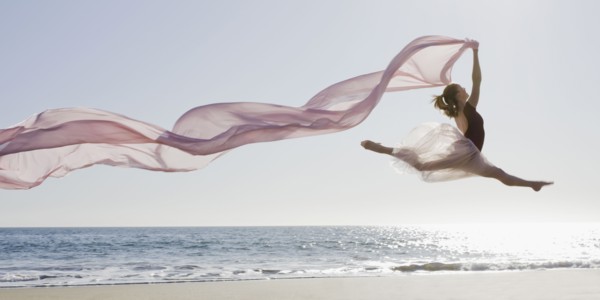Dancer leaping on beach. Photographe : PT Images