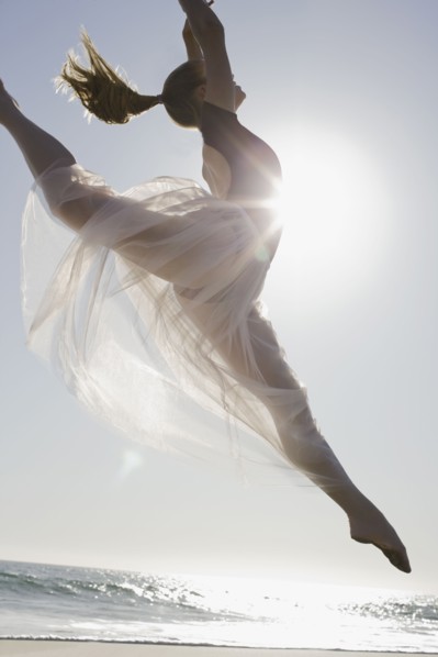 Dancer leaping on beach. Photographe : PT Images