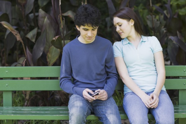 Young couple sitting on park bench. Photographe : PT Images