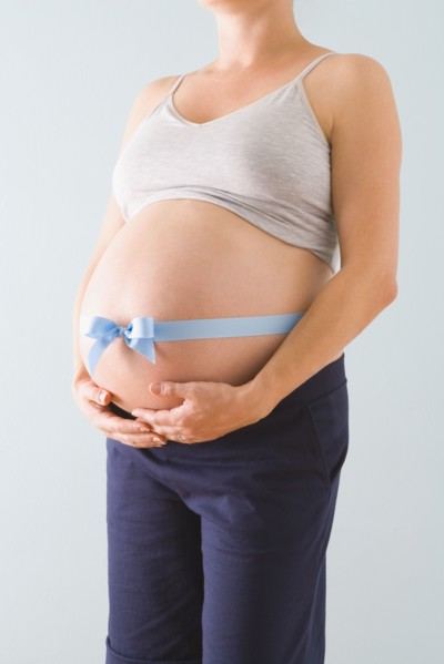Pregnant woman’s belly wrapped in blue ribbon. Photographe : Jennifer L. Boggs