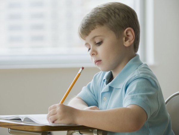 Boy writing in classroom.