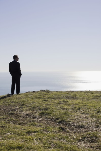 Businessman looking toward ocean. Photographe : PT Images