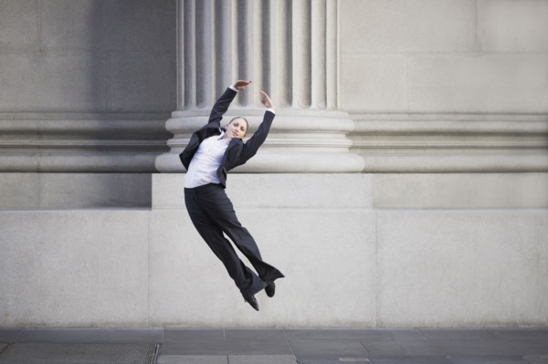 Businesswoman dancing in urban setting. Photographe : PT Images