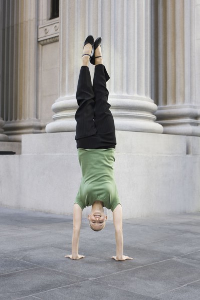 Businesswoman doing handstand on urban sidewalk. Photographe : PT Images