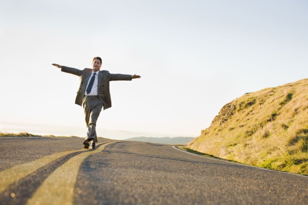 Businessman running on remote road. Photographe : PT Images