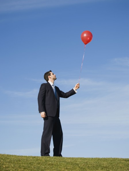 Businessman holding red balloon.