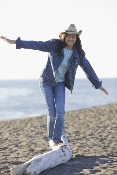 Teenage girl balancing on driftwood. Photographe : PT Images