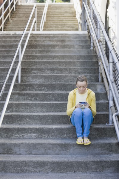 Girl text messaging on steps. Photographe : PT Images