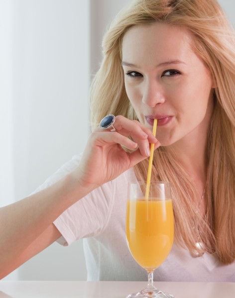 Portrait of young woman drinking orange juice. Photographe : Jamie Grill