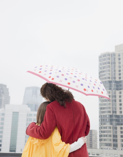 USA, New York City, mother and daughter (10-12 years) embracing under umbrella, rear view, Jersey