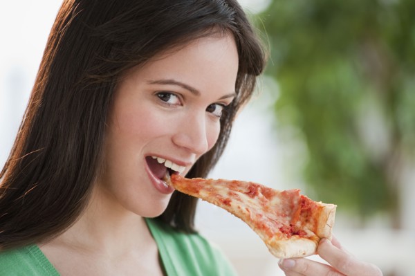 Portrait of woman eating pizza slice. Photographe : Daniel Grill