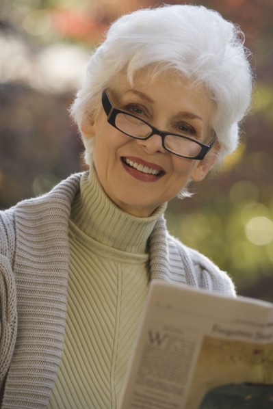 Portrait of senior woman reading newspaper outdoors. Photographe : mark edward atkinson
