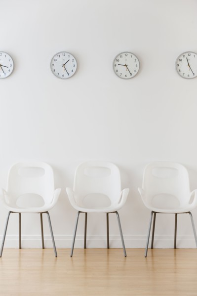 Row of chairs in waiting room under clocks displaying time zones.