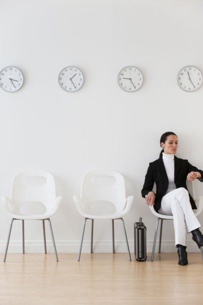 Businesswoman looking at wrist watch in waiting room.