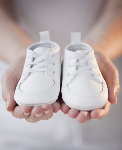 Close-up of woman holding baby shoes.