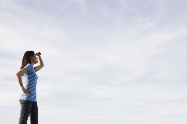Woman shielding eyes against sky. Photographe : PT Images