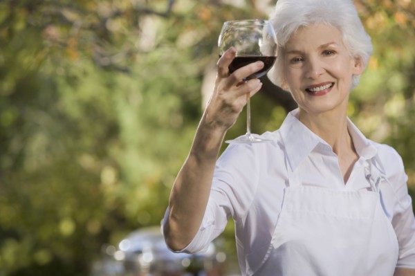 Senior woman holding glass of red wine, portrait. Photographe : mark edward atkinson