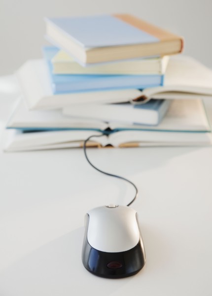 Computer mouse near pile of books, studio shot. Photographe : Jamie Grill
